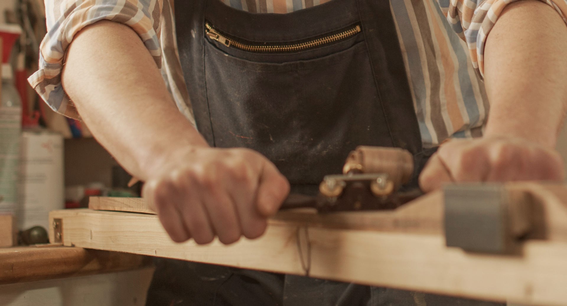 Detailaufnahme von Händen in einer Werkstatt, die einen Hobel verwenden
